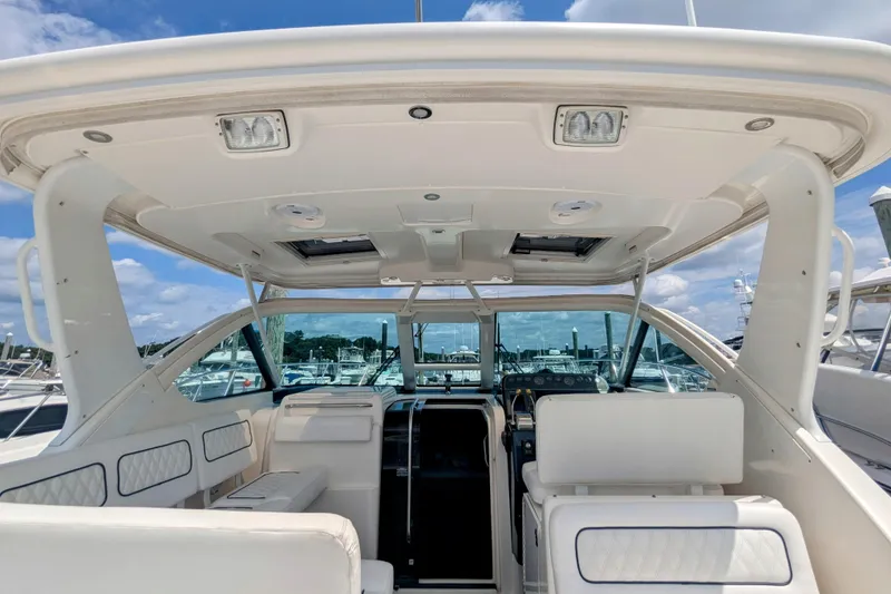 Slide: The Image of 2005 Tiara Yachts 3200 Open cockpit with white seating and helm, under a clear sky. - 12