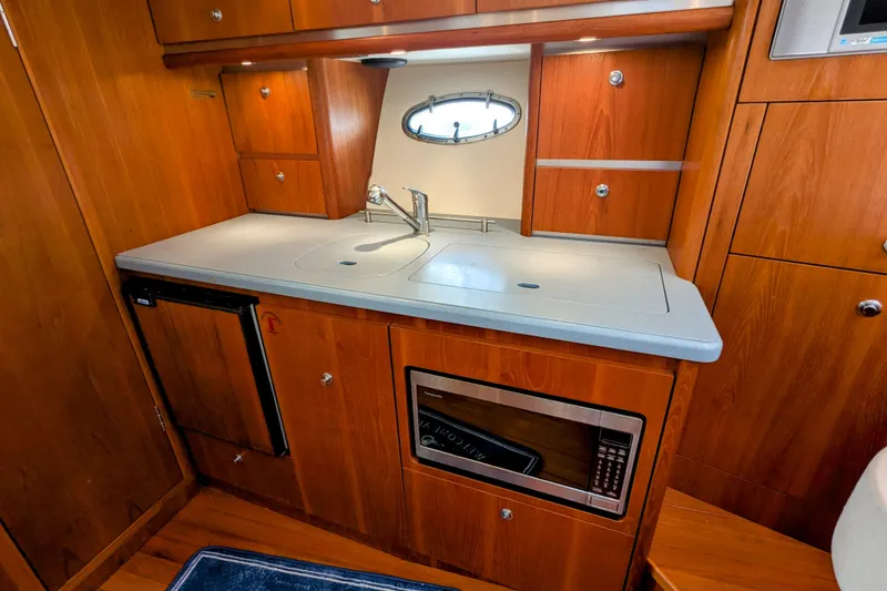 Slide: The Image of 2005 Tiara Yachts 3200 Open galley with wood cabinetry, sink, and microwave. - 19