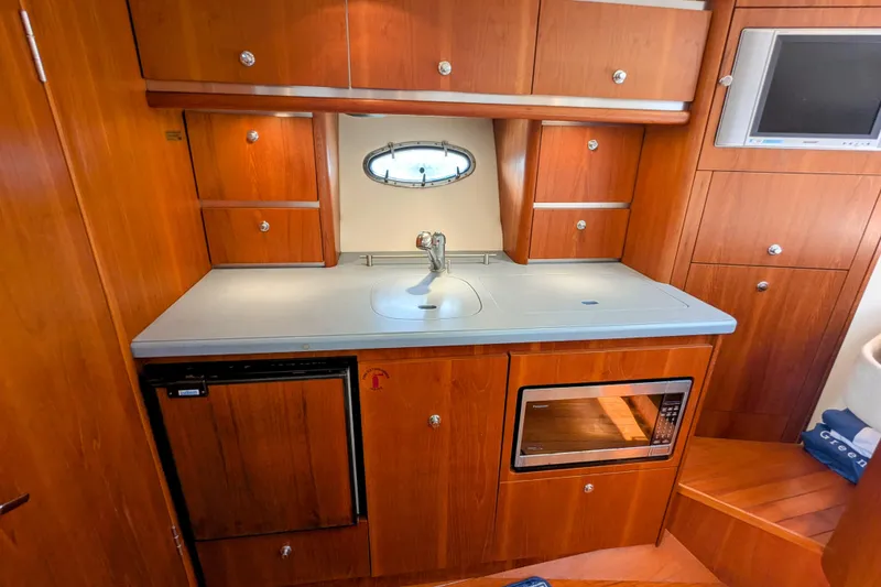 Slide: The Image of 2005 Tiara Yachts 3200 Open galley with wood cabinetry, sink, microwave, and mini-fridge. - 23