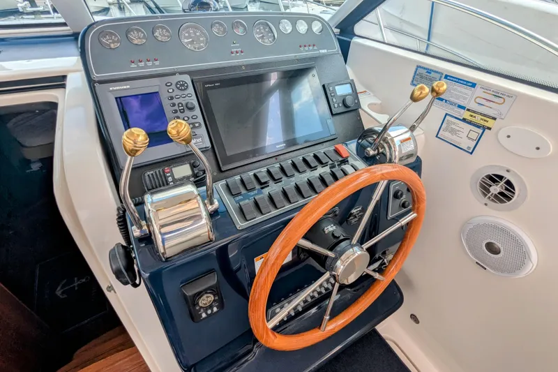 Slide: The Image of 2005 Tiara Yachts 3200 Open helm with wooden steering wheel and modern navigation controls. - 5