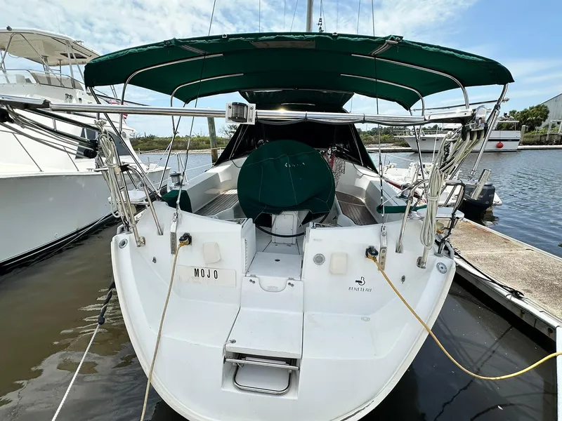Slide: The Image of 1998 Beneteau 381 sailboat docked, featuring green canopy and white hull. - 17
