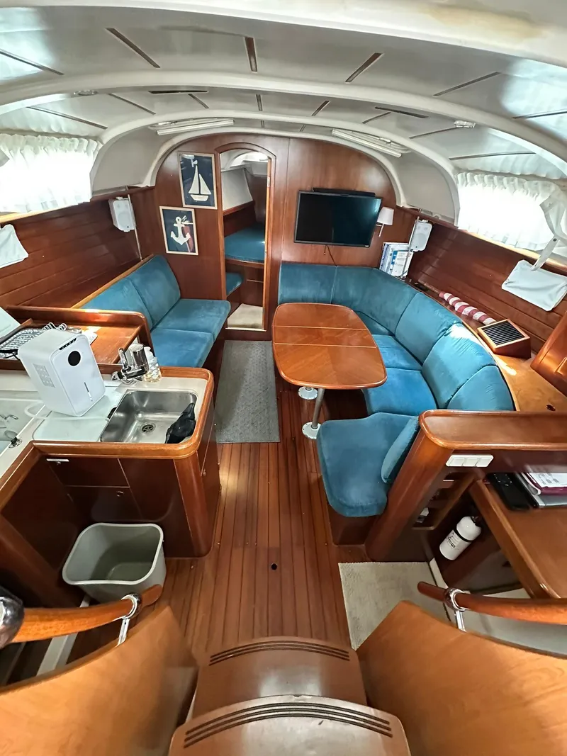 Slide: The Image of Interior of 1998 Beneteau 381 yacht with blue seating, wooden finishes, and kitchenette. - 23