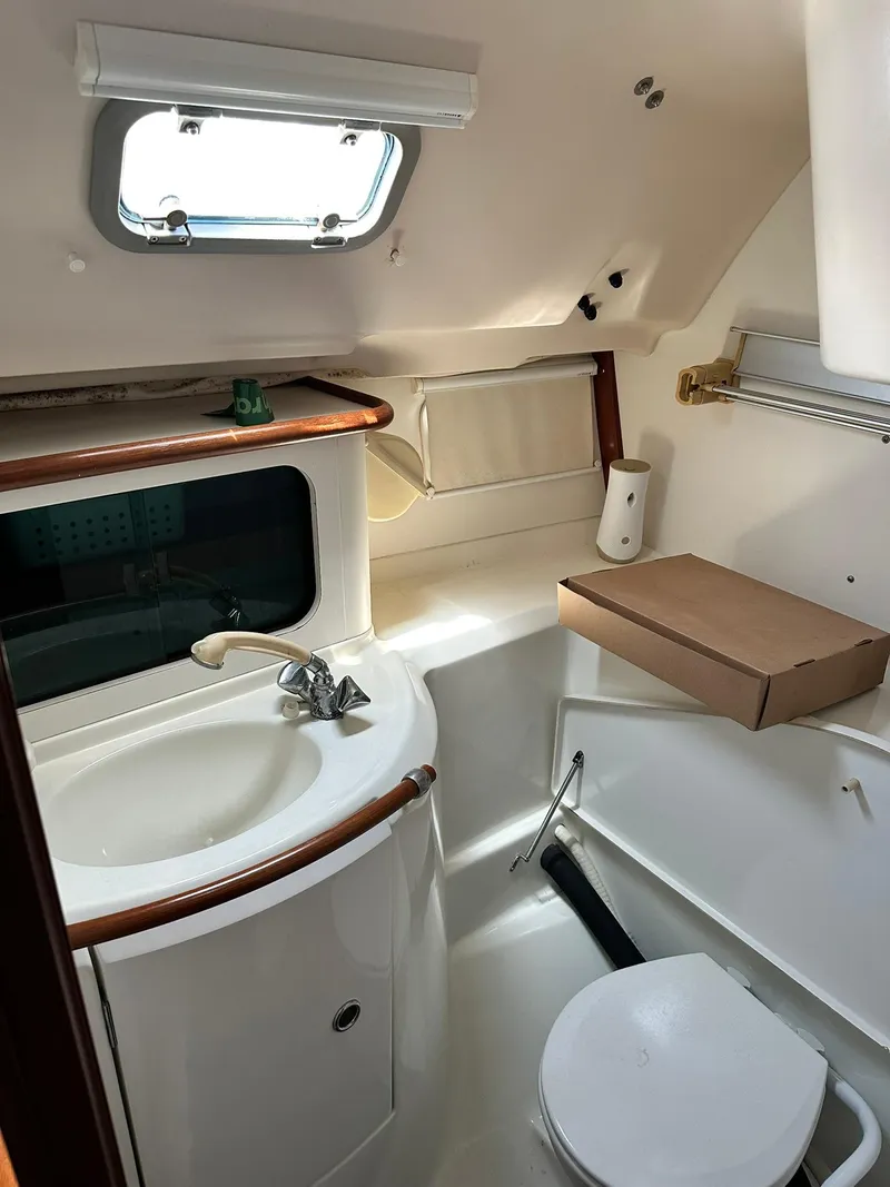 Slide: The Image of 1998 Beneteau 381 yacht bathroom with sink, toilet, and porthole window. - 27