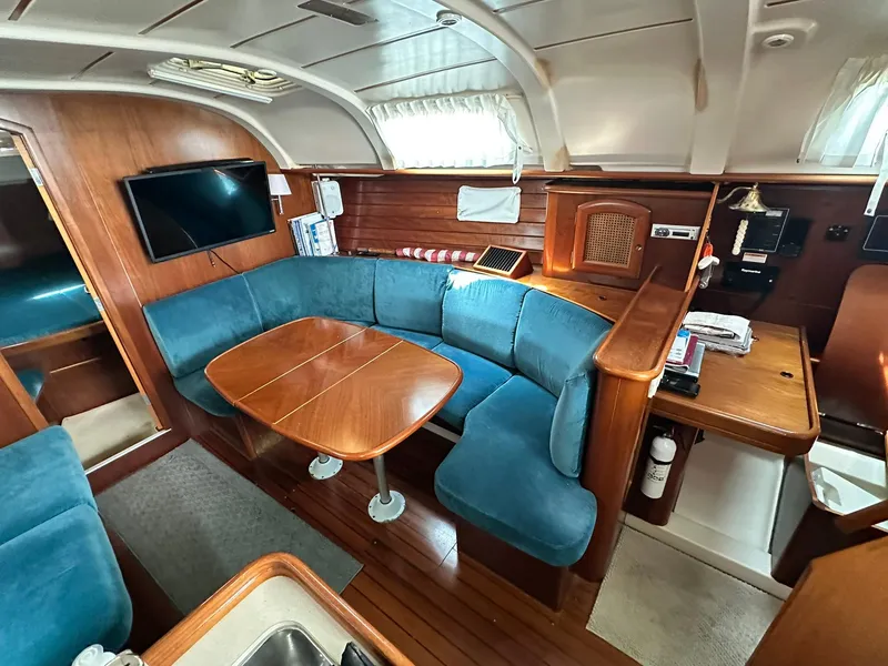 Slide: The Image of Interior of 1998 Beneteau 381 yacht with blue seating, wooden table, and mounted TV. - 31