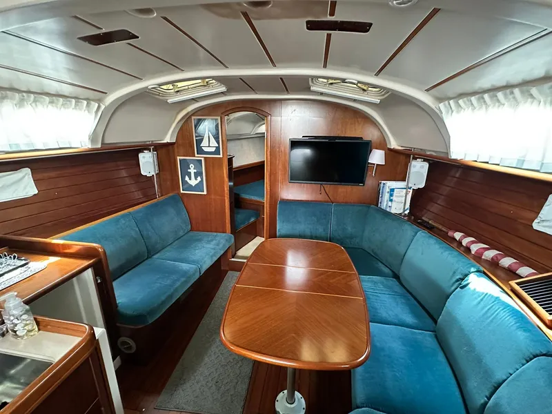 Slide: The Image of Interior of 1998 Beneteau 381 sailboat with blue seating and wooden table. - 33
