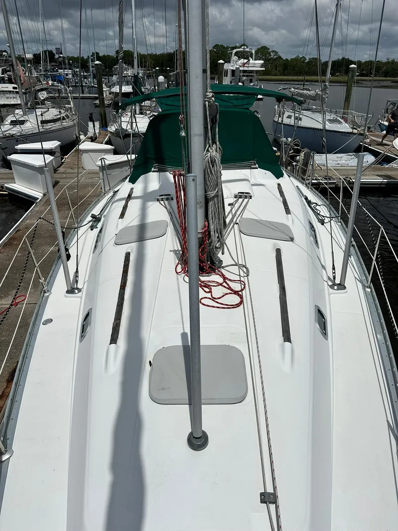 Slide: The Image of 1998 Beneteau 381 sailboat docked at marina, featuring green canopy and clean deck. - 6