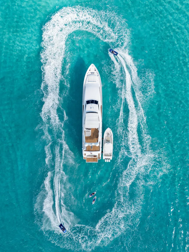 Slide: The Image of Aerial view of 2004 Ferretti Yachts 112 Custom Line surrounded by jet skis in turquoise water. - 4