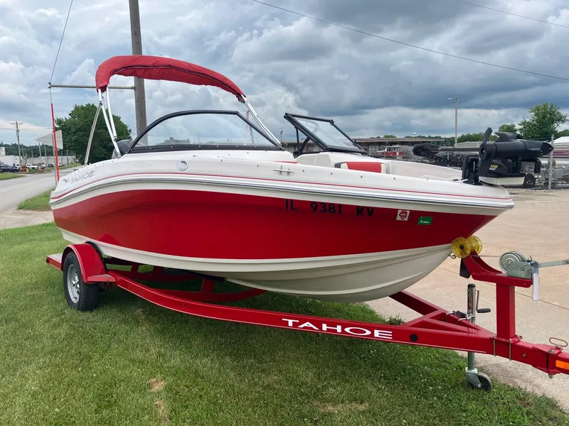 The Image of Red 2016 Tahoe 450 TF boat on trailer, parked on grass under cloudy sky. - 0
