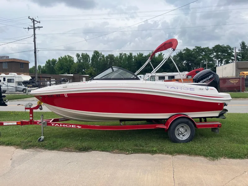 Slide: The Image of Red 2016 Tahoe 450 TF boat on trailer, parked on grass, under cloudy sky. - 1
