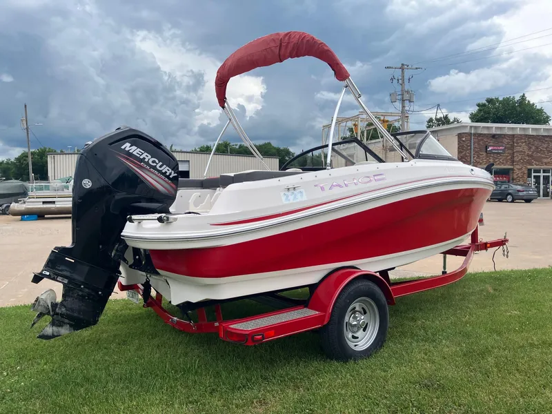 Slide: The Image of 2016 Tahoe 450 TF boat with Mercury engine on red trailer, parked on grass. - 2