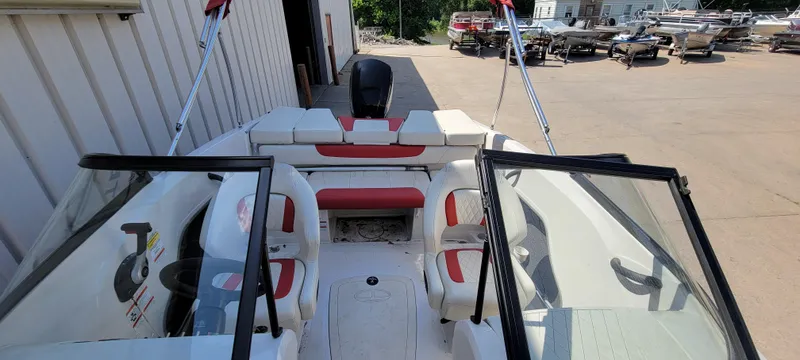 Slide: The Image of 2016 Tahoe 450 TF boat interior with red and white seating, parked outdoors. - 25