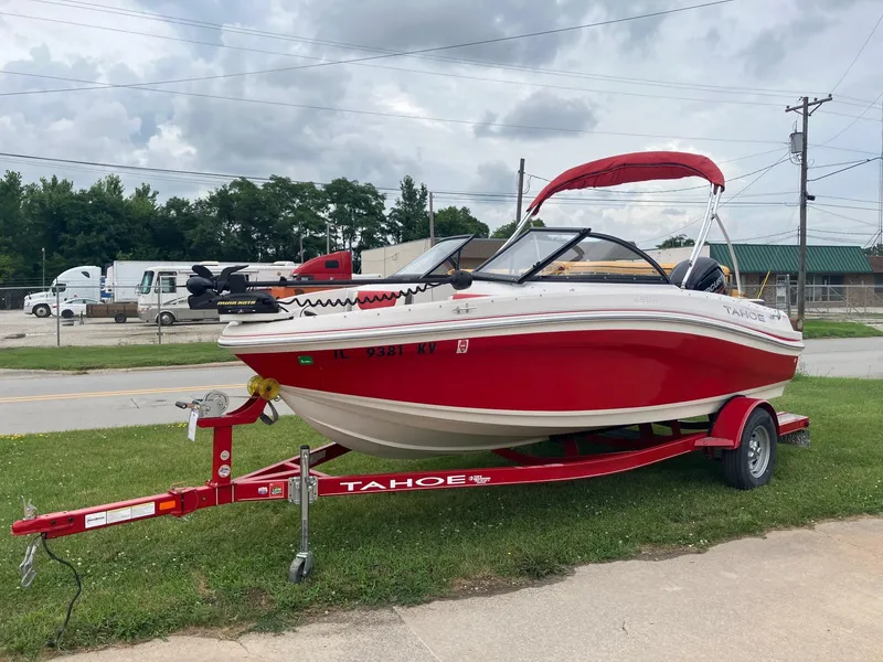 Slide: The Image of 2016 Tahoe 450 TF boat on red trailer, parked outdoors under cloudy sky. - 3