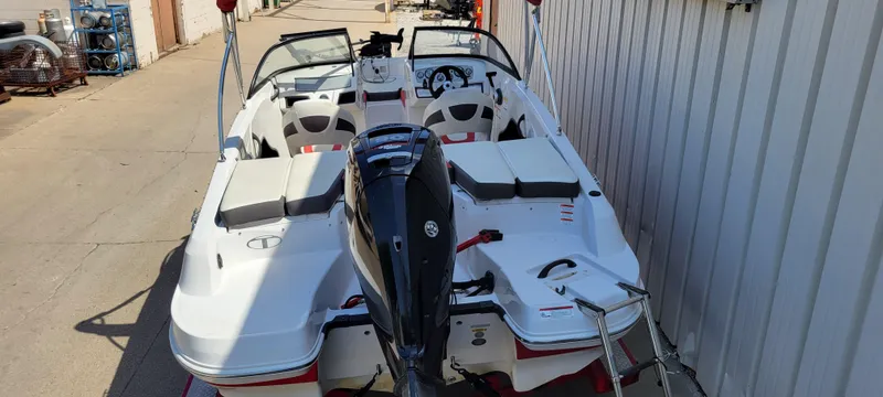 Slide: The Image of 2016 Tahoe 450 TF boat with outboard motor, docked beside a metal building. - 34