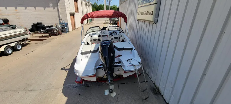 Slide: The Image of 2016 Tahoe 450 TF boat with red canopy, parked beside a building. - 35