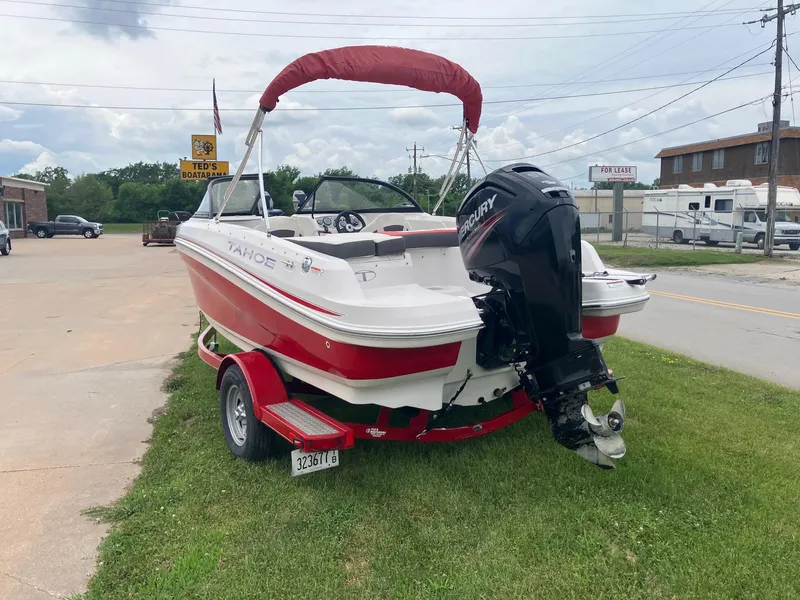 Slide: The Image of 2016 Tahoe 450 TF boat with Mercury engine on red trailer, parked on grass. - 5