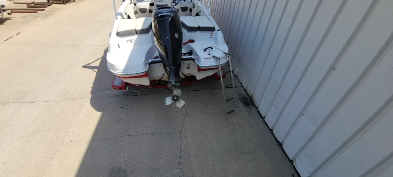 Slide: The Image of 2016 Tahoe 450 TF boat with outboard motor and ladder, parked beside a building. - 6