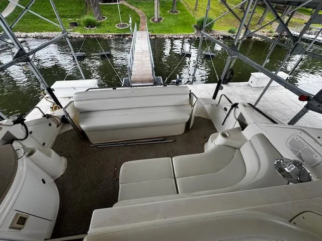 Slide: The Image of 2004 Regal Commodore 4260 boat interior with white seating, docked by a scenic waterfront. - 35