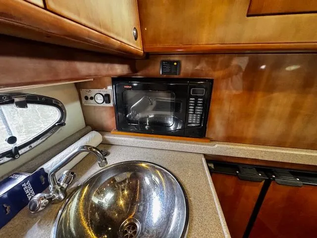 Slide: The Image of 2004 Regal Commodore 4260 yacht kitchen with microwave, sink, and wooden cabinetry. - 42