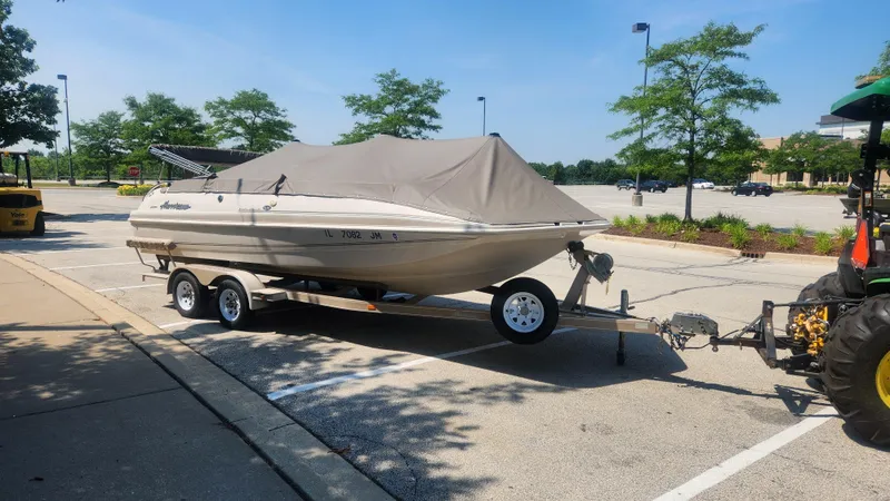 Slide: The Image of Covered 2001 Hurricane 201GS boat on trailer in parking lot, attached to a tractor. - 16