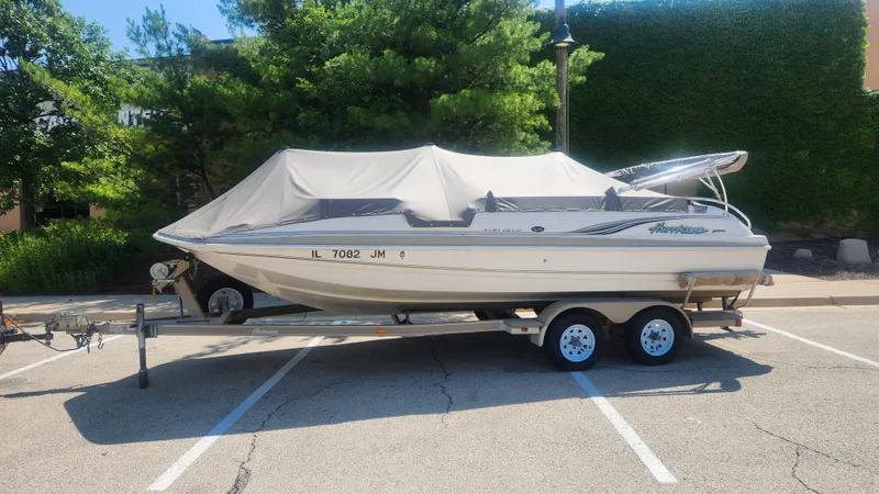 Slide: The Image of 2001 Hurricane 201GS boat on trailer, covered, parked in sunny lot. - 2