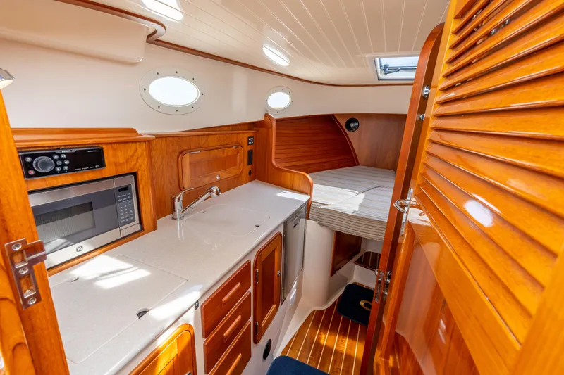 Slide: The Image of 2018 Hinckley Picnic Boat MKII interior with kitchenette and cozy sleeping area. - 16
