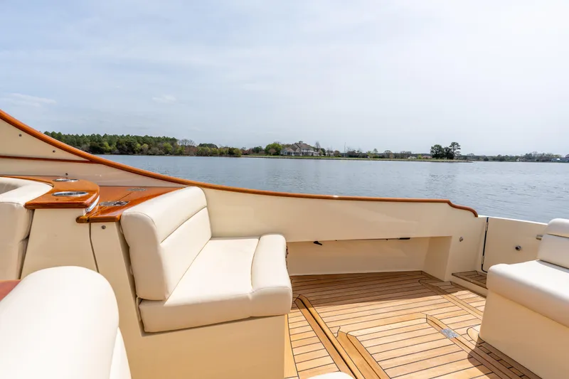 Slide: The Image of 2018 Hinckley Picnic Boat MKII interior with lake view, featuring elegant seating and wooden deck. - 6