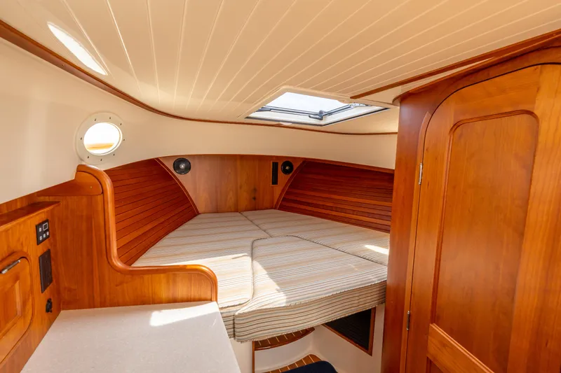 Slide: The Image of 2018 Hinckley Picnic Boat MKII cabin interior with wood finish and cozy bed. - 14
