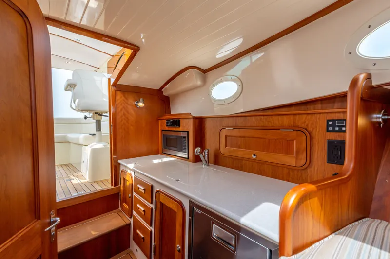 Slide: The Image of 2018 Hinckley Picnic Boat MKII interior with wooden cabinetry and modern amenities. - 17