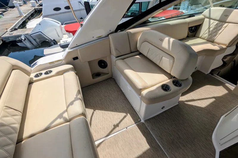 Slide: The Image of 2018 Regal 33 XO boat interior with beige seating and cup holders at a marina. - 10