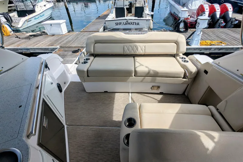 Slide: The Image of 2018 Regal 33 XO boat interior with beige seating and cup holders at a marina. - 11