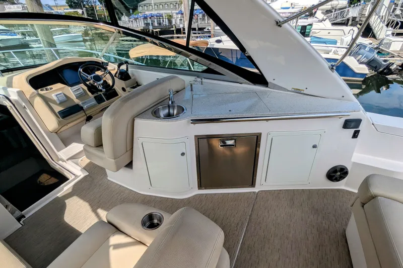 Slide: The Image of 2018 Regal 33 XO boat interior with helm, sink, and seating area at marina. - 13