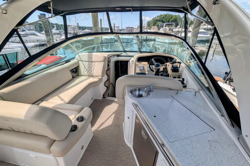 Slide: The Image of 2018 Regal 33 XO boat interior with seating, kitchenette, and steering wheel at a marina. - 7