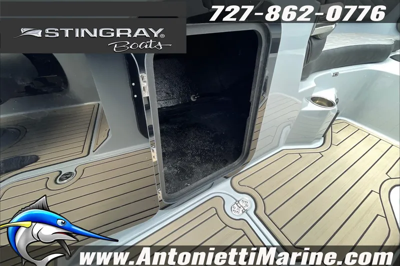 Slide: The Image of 2026 Stingray 23 OSX boat interior with storage compartment, teak flooring, and contact details. - 23