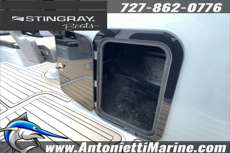 Slide: The Image of 2026 Stingray 23 OSX boat storage compartment, open on deck, with contact details and logo. - 25