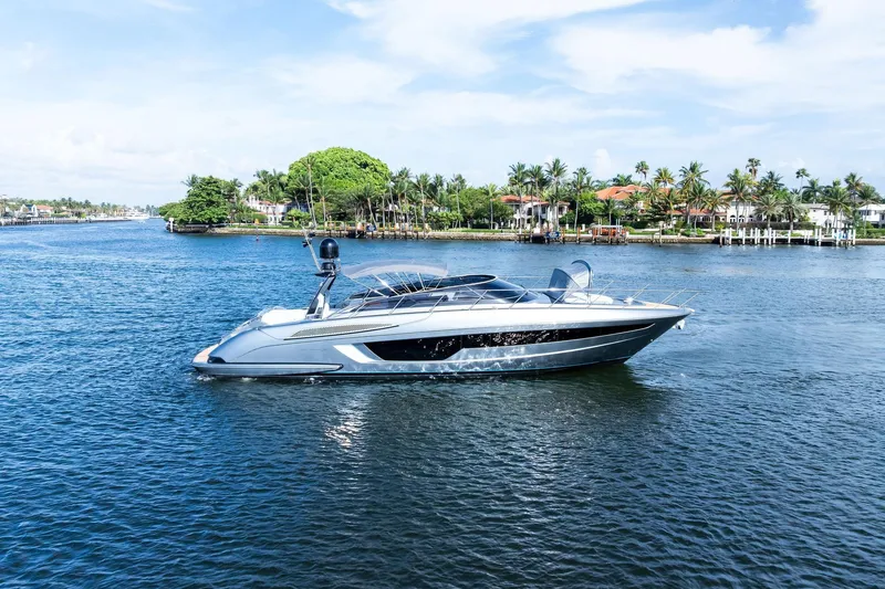 The Image of 2019 Riva 56' Rivale yacht cruising on a scenic waterway with lush greenery. - 0