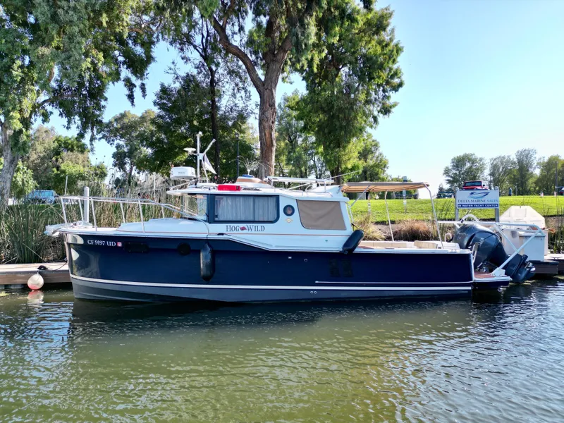 Slide: The Image of 2023 Ranger Tugs R-27 boat docked by lush greenery and calm waters. - 10