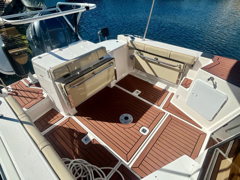 Slide: The Image of 2023 Ranger Tugs R-27 boat deck with teak flooring and seating, docked by the water. - 13