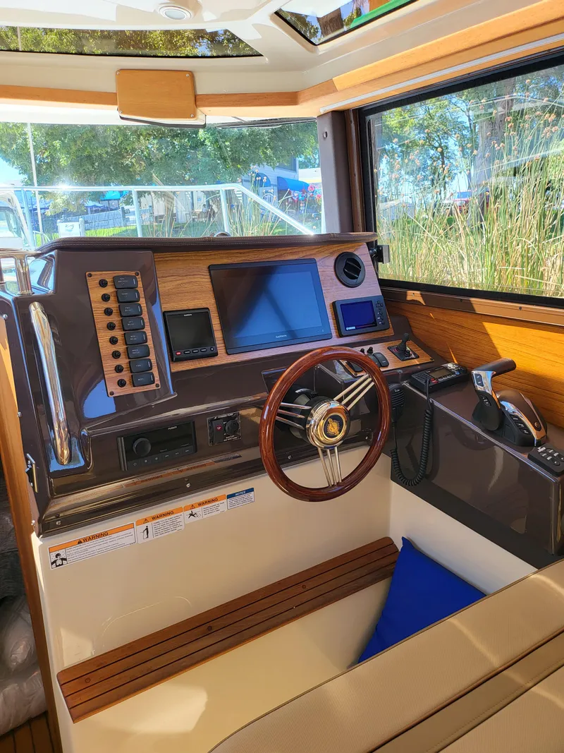 Slide: The Image of 2023 Ranger Tugs R-27 helm with modern controls and wooden accents. - 14