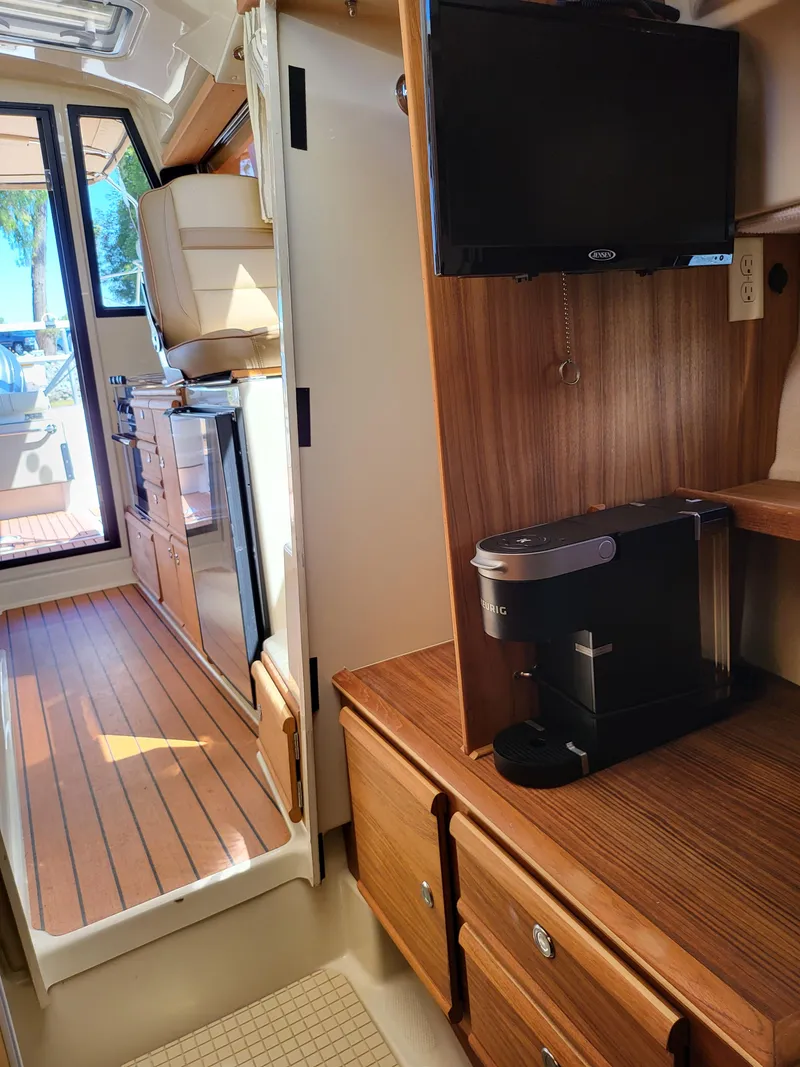 Slide: The Image of Interior of 2023 Ranger Tugs R-27 with kitchenette, TV, and coffee maker. - 17