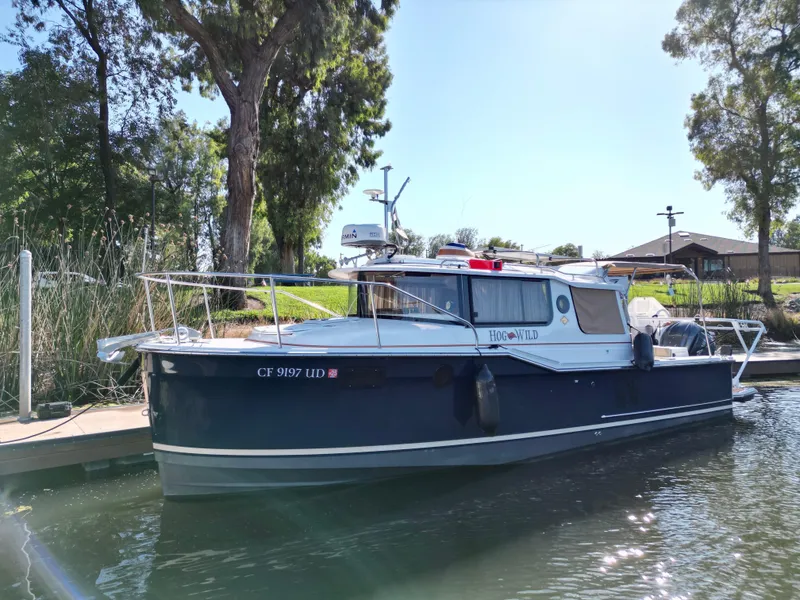 Slide: The Image of 2023 Ranger Tugs R-27 boat docked in a serene marina setting. - 2
