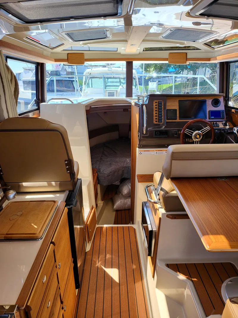 Slide: The Image of Interior of 2023 Ranger Tugs R-27 boat, featuring wood finishes and modern navigation equipment. - 21