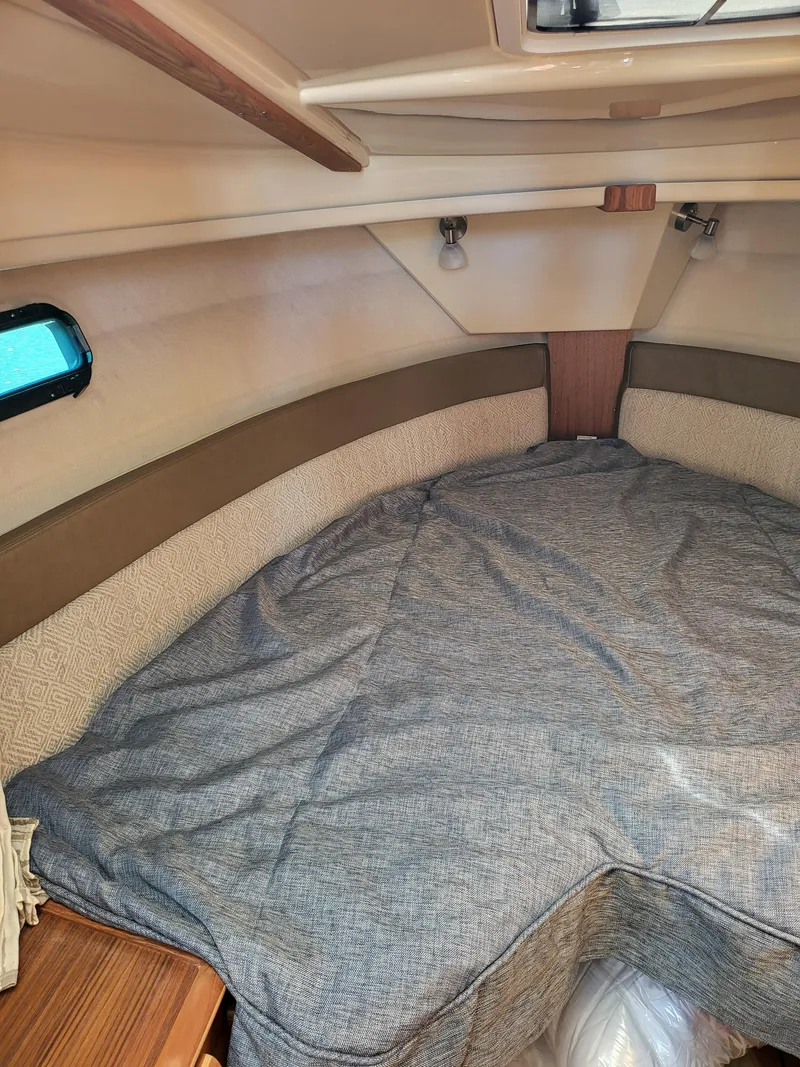 Slide: The Image of 2023 Ranger Tugs R-27 cabin interior with cozy bed and wooden accents. - 24