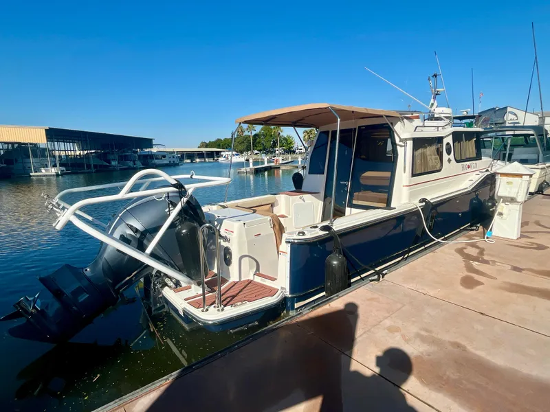 Slide: The Image of 2023 Ranger Tugs R-27 boat docked at marina, featuring outboard motor and spacious deck. - 3
