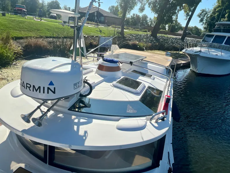 Slide: The Image of 2023 Ranger Tugs R-27 boat docked, featuring Garmin xHD radar, sunny day, lush greenery. - 4