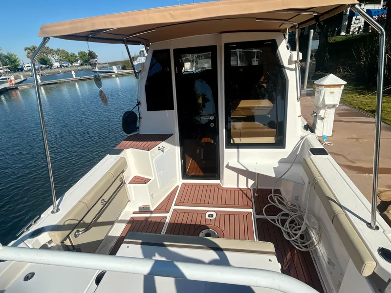 Slide: The Image of 2023 Ranger Tugs R-27 boat with spacious deck and seating, docked by the water. - 9