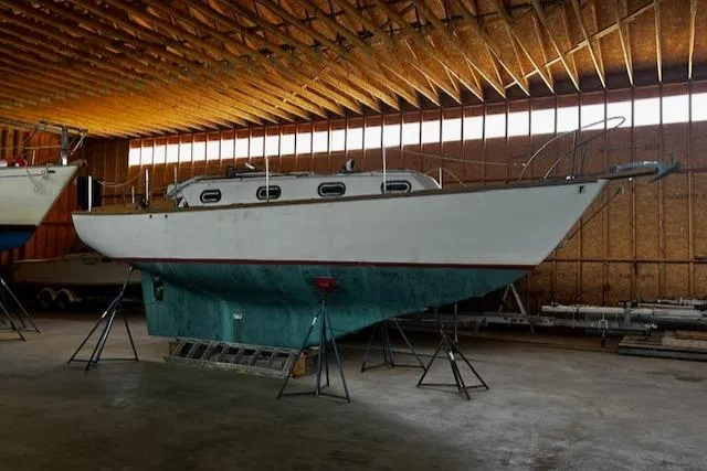 Slide: The Image of 1977 Cape Dory Sloop sailboat in indoor storage, supported by stands. - 2