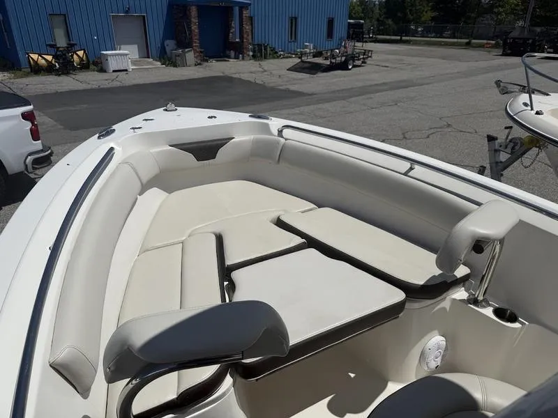 Slide: The Image of 2023 Sailfish 220 boat interior with cushioned seating and table in a marina setting. - 12