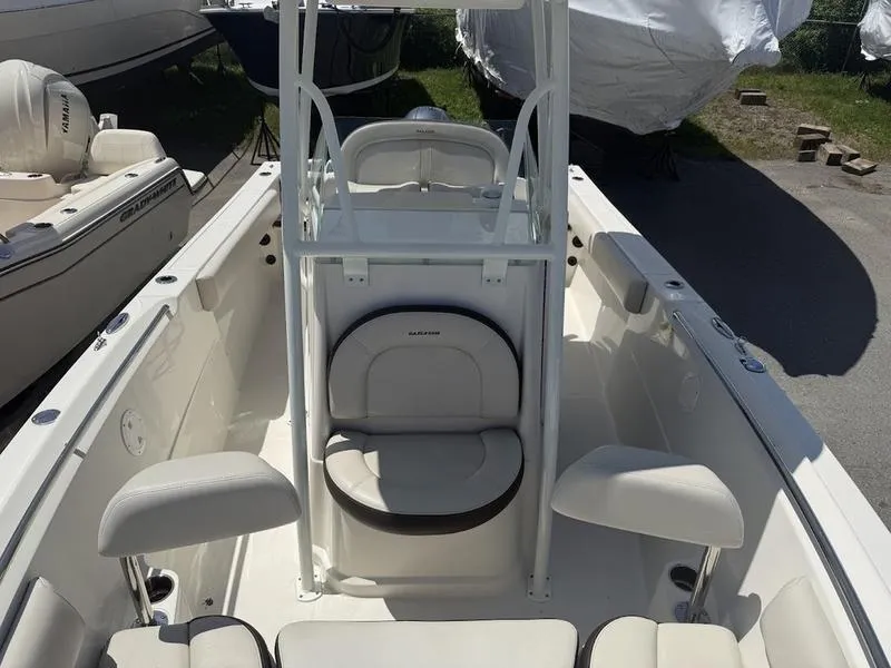 Slide: The Image of 2023 Sailfish 220 boat interior with seating and console, parked outdoors. - 7