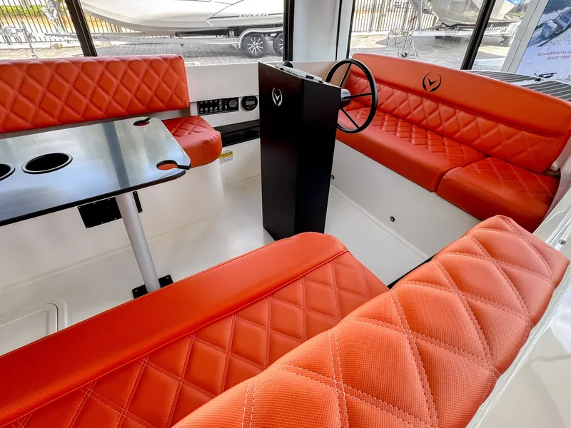 Slide: The Image of 2024 Vision Marine Fantail 217 interior with red quilted seating and black table. - 6
