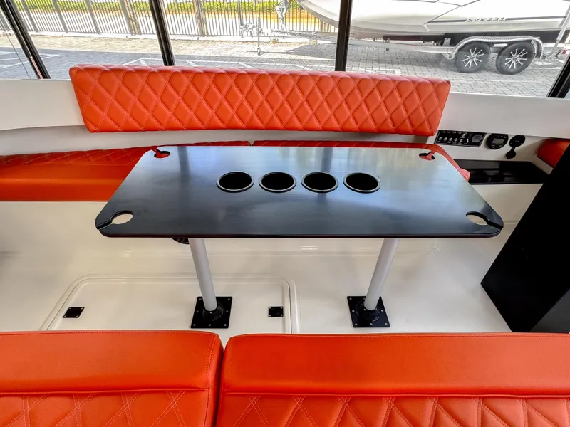 Slide: The Image of 2024 Vision Marine Fantail 217 interior with orange seating and black table. - 7